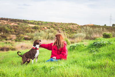 Rear view of woman with dog sitting on field