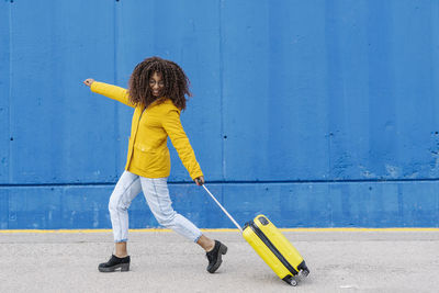 Full length of woman standing against yellow wall