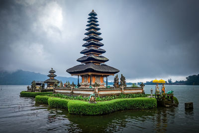 Traditional building by lake against sky