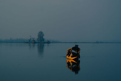 Rear view of people on lake against sky during winter