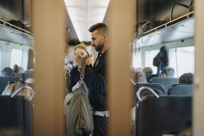 Man holding luggage while traveling in train with family