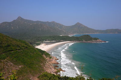 Scenic view of sea and mountains against clear blue sky