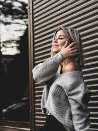 Young woman looking away standing against metallic built structure