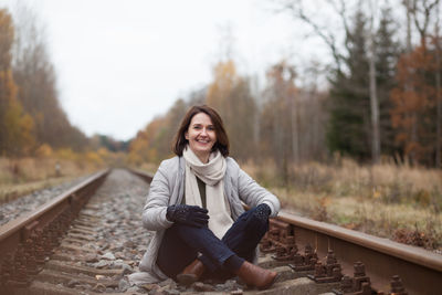 Portrait of a smiling young woman standing on railroad track