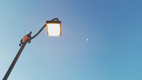 Low angle view of illuminated street light against clear blue sky