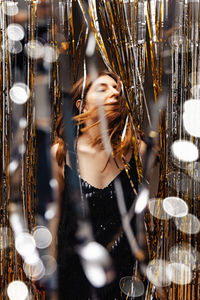 Digital composite image of woman holding illuminated string lights