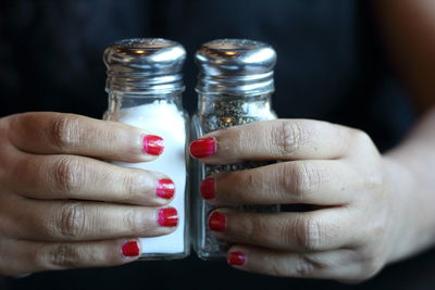 Midsection of woman holding salt and pepper shakers