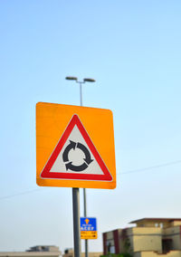 Low angle view of road sign against clear blue sky