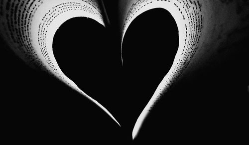 Close-up of heart shape on book against black background