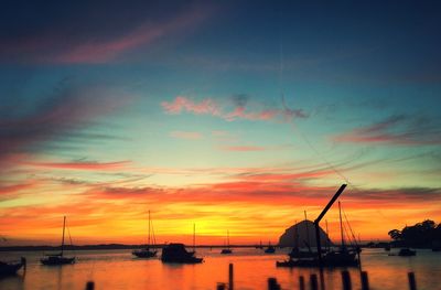 Silhouette sailboats in sea against sky during sunset