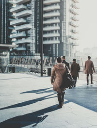 Rear view of people walking on street against buildings