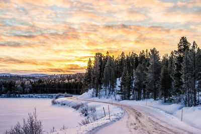 Snow covered landscape against cloudy sky