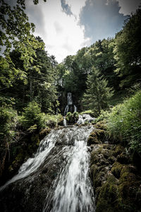 Scenic view of waterfall against sky