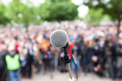 Close-up of microphone against crowd in city