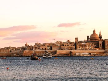 Boats in sea against buildings in city