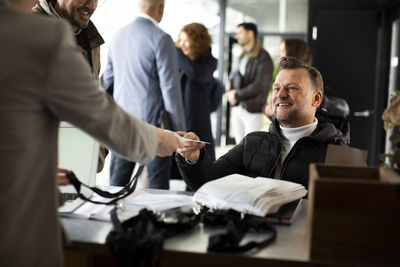 Smiling disabled businessman taking id card from receptionist at registering counter