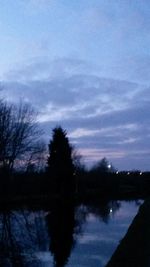 Bare trees against cloudy sky