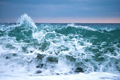 Waves splashing in sea against sky