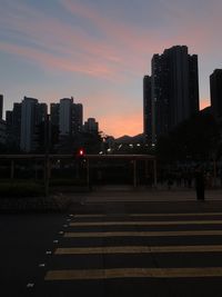 Street amidst buildings against sky during sunset