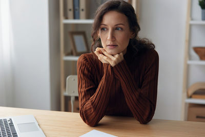 Portrait of young woman using laptop at home