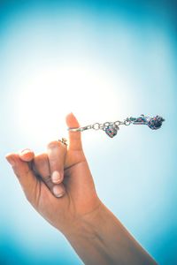 Cropped image of woman spinning key ring against clear blue sky