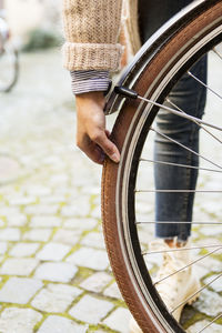 Low section of businesswoman examining bicycle tire on sidewalk