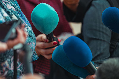 News reporters interviewing a group unrecognizable people outdoors