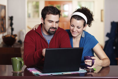 Couple work on laptop computer at home