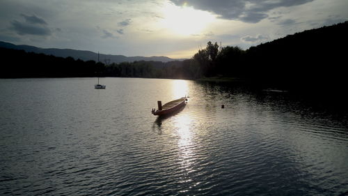 Silhouette boat in lake against sky during sunset