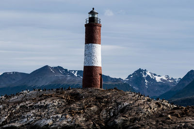 Lighthouse on snow covered mountain against sky