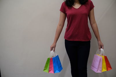 Midsection of woman holding umbrella standing against wall