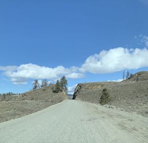 Road amidst land against blue sky