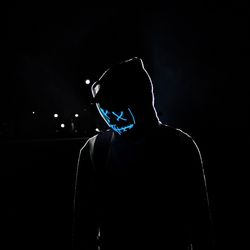 Silhouette man wearing mask against black background