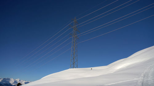 Low angle view of electricity pylon against clear blue sky