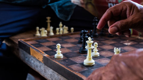 Midsection of person holding chess pieces on table