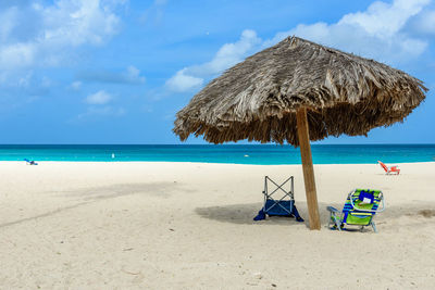 Deck chairs on beach against sky