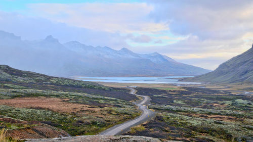 Scenic view of road by mountains against sky