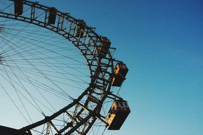 Low angle view of ferris wheel against clear blue sky