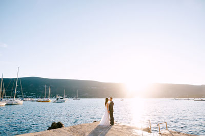 Couple standing at pier near sea