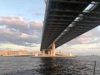 Bridge over sea by buildings in city against sky