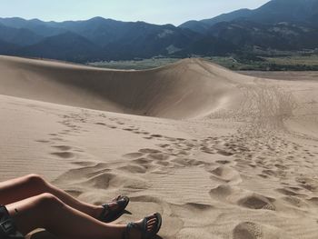 Low section of woman sitting on sand
