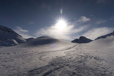 Scenic view of snowcapped mountains against sky with ski tracks