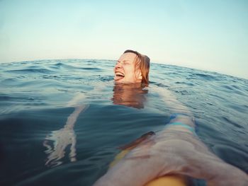 Woman swimming in sea against sky