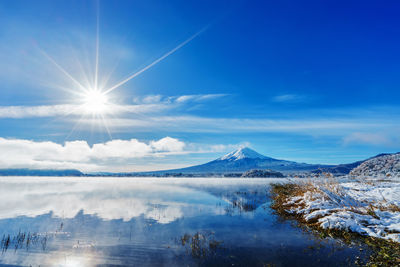 Scenic view of lake and mountains against blue sky