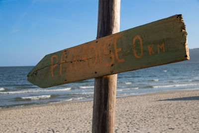 Close-up of text on beach against sky