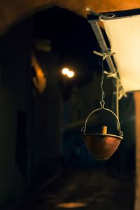 Close-up of illuminated lamp hanging on metal at night