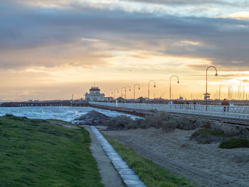 Road by sea against sky during sunset