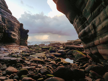 Rock formations on beach against sky