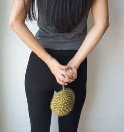 Midsection of woman holding umbrella standing against wall
