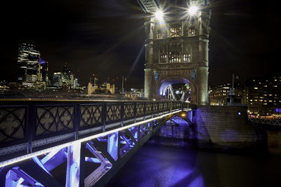 Illuminated bridge over river in city at night